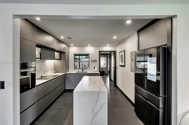 a large kitchen with stainless steel appliances kitchen island a large counter top and a refrigerator