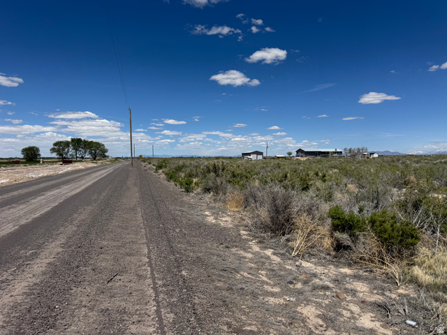 2225 South 500th Street East Delta, UT 84624 - Photo 4 of 9 Expansive rural landscape featuring a gravel road, distant structures, and natural vegetation under a clear sky. 10.75 acres on the outskirts of Delta.