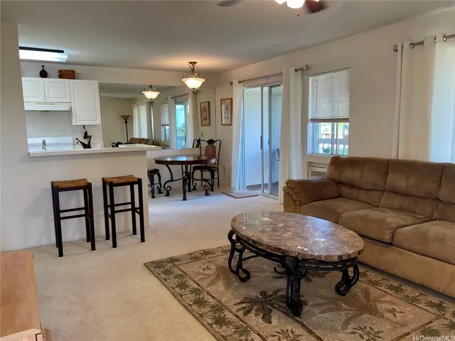 a living room with furniture a dining table and a refrigerator