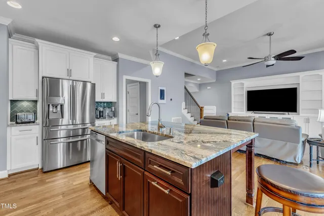 a kitchen with stainless steel appliances granite countertop a sink a stove and a wooden floors