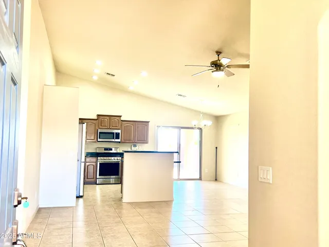 a view of a kitchen with kitchen island a sink stainless steel appliances and cabinets