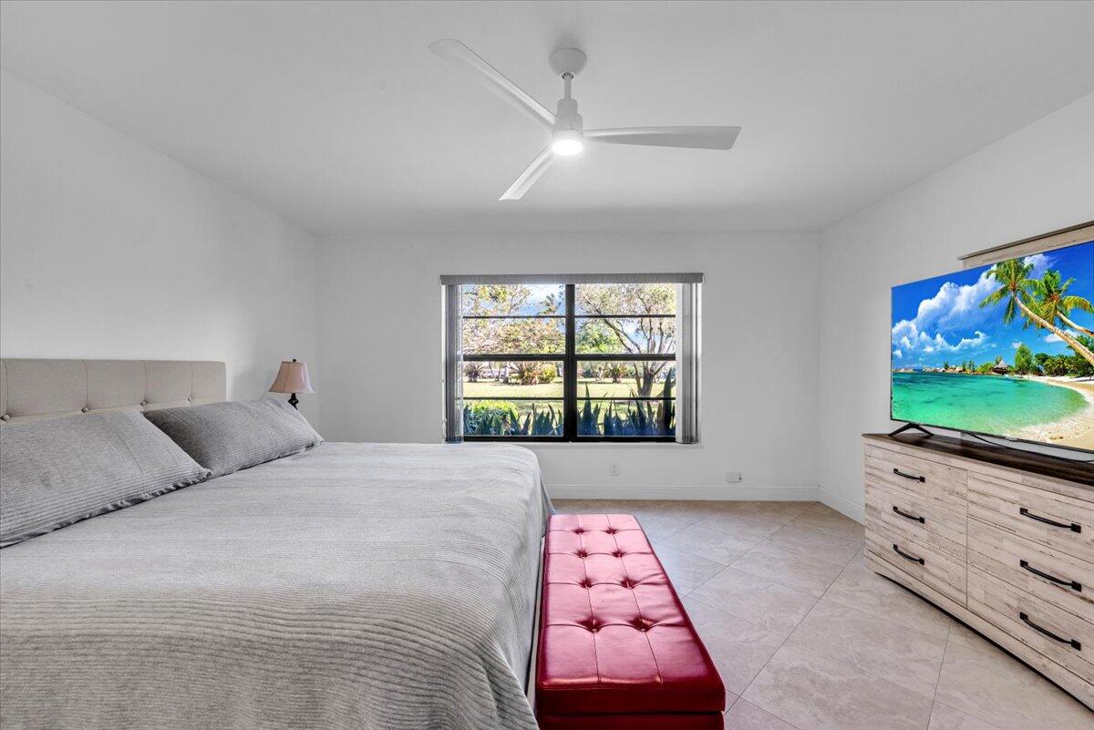 300 North Hwy A1A, Unit 103M Jupiter, FL 33477 - Photo 11 of 25 a bedroom with a bed and a flat tv screen on dresser