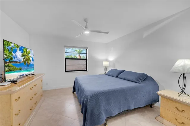 a bedroom with a bed and a flat screen tv on the dresser next to a window
