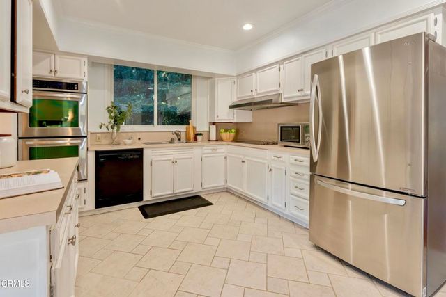 a kitchen with white cabinets and appliances