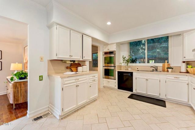a kitchen with stainless steel appliances granite countertop white cabinets and a window