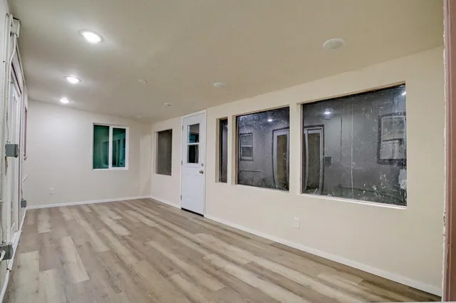 a view of an empty room with window and wooden floor