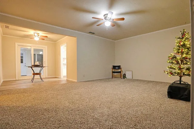 a view of an empty room with a chandelier fan and a fireplace