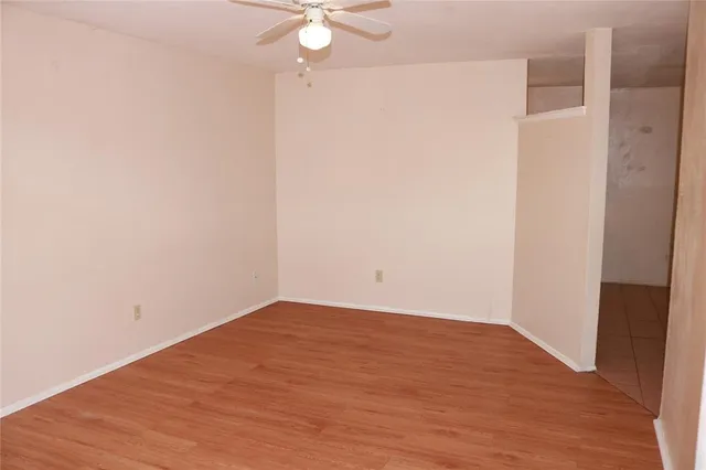 an empty room with wooden floor and fan