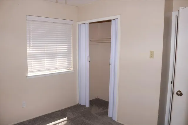 a view of an empty room with closet and a window