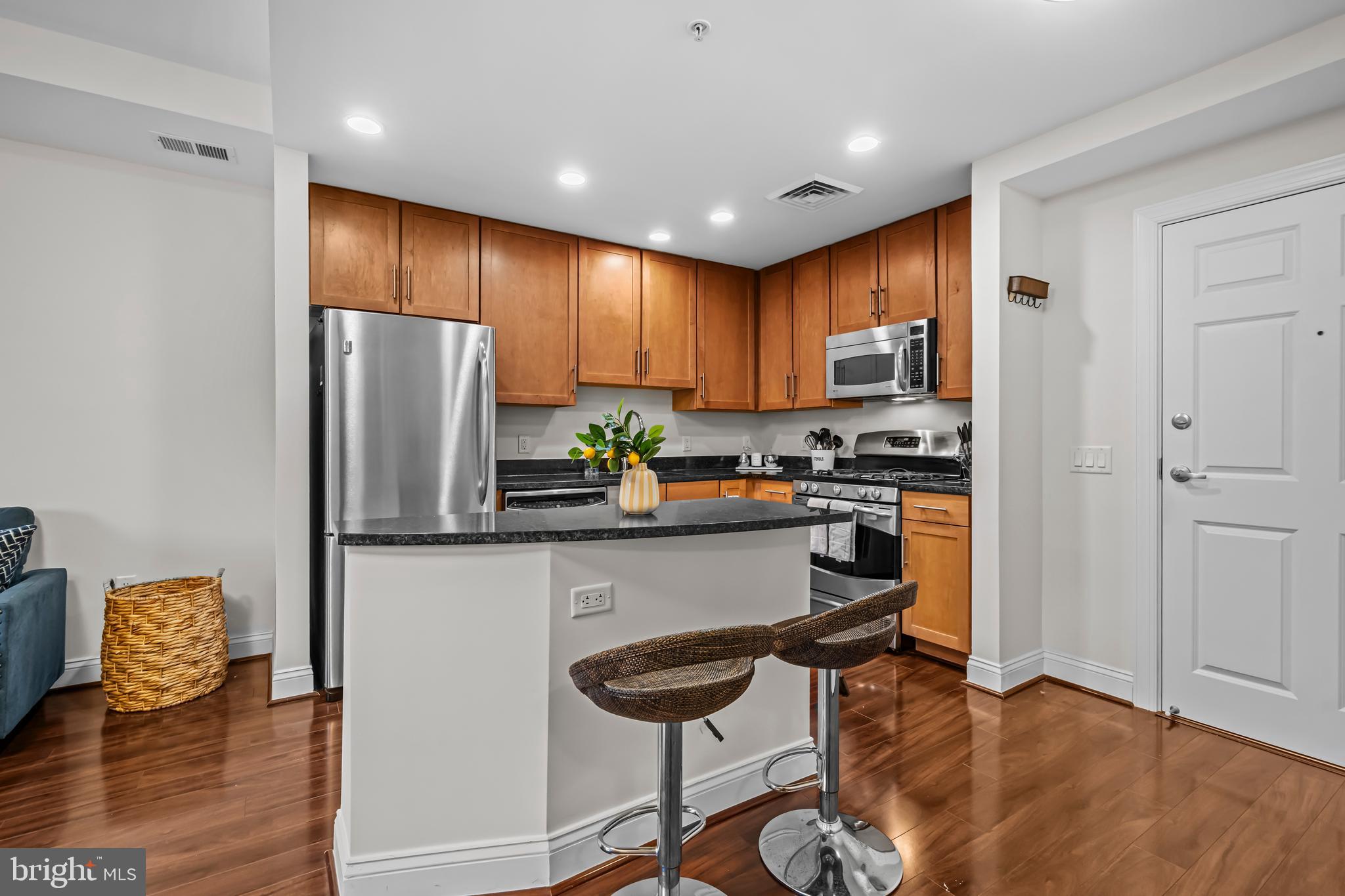 1111 Oronoco Street, Unit 326 Alexandria, VA 22314 - Photo 12 of 54 a kitchen with stainless steel appliances granite countertop a refrigerator a stove a sink and a dining table with wooden floor