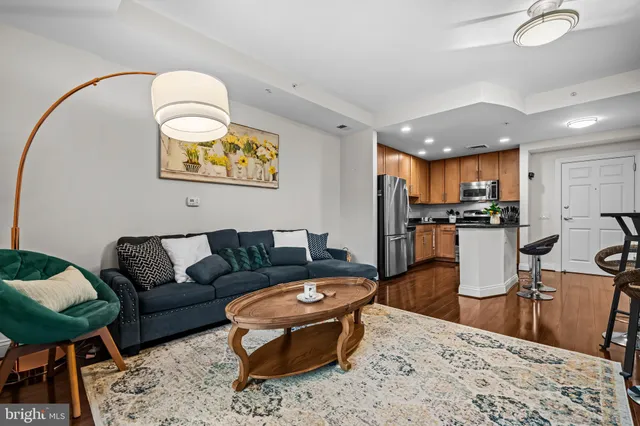 a living room with stainless steel appliances kitchen island granite countertop a couch and wooden floor