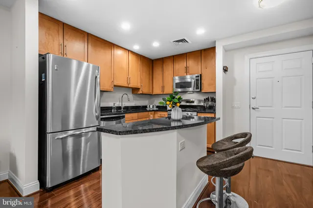 a kitchen with stainless steel appliances granite countertop a refrigerator a sink a stove a dining table and chairs