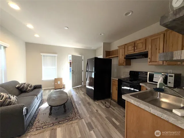 a kitchen with stainless steel appliances granite countertop a refrigerator a sink a stove a dining table and chairs with wooden floor