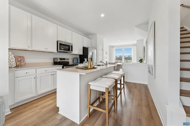 a kitchen with white cabinets stainless steel appliances and wooden floor
