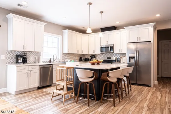 a kitchen with stainless steel appliances granite countertop a sink a stove a refrigerator and island with wooden floor