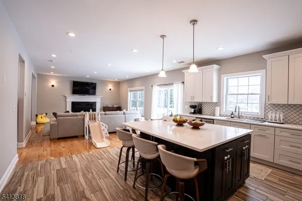 a kitchen with a stove a sink dishwasher a dining table and chairs with wooden floor
