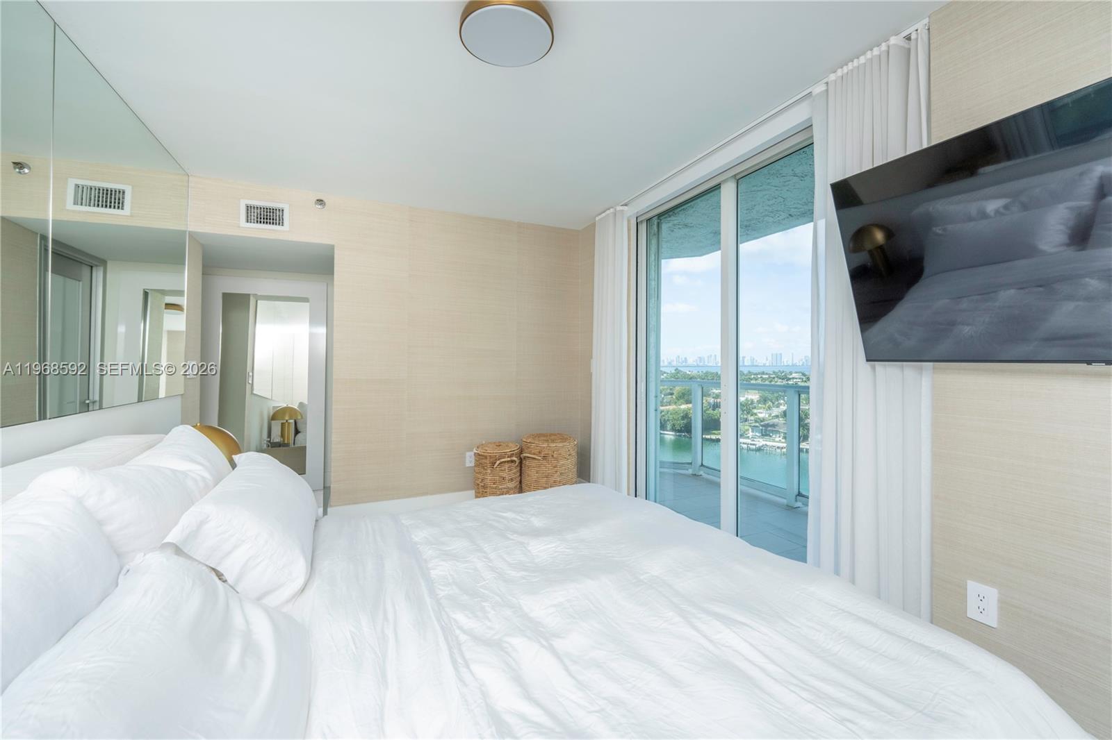 5900 Collins Avenue, Unit 1401 Miami Beach, FL 33140 - Photo 27 of 51 a bedroom with a large bed and a flat tv screen