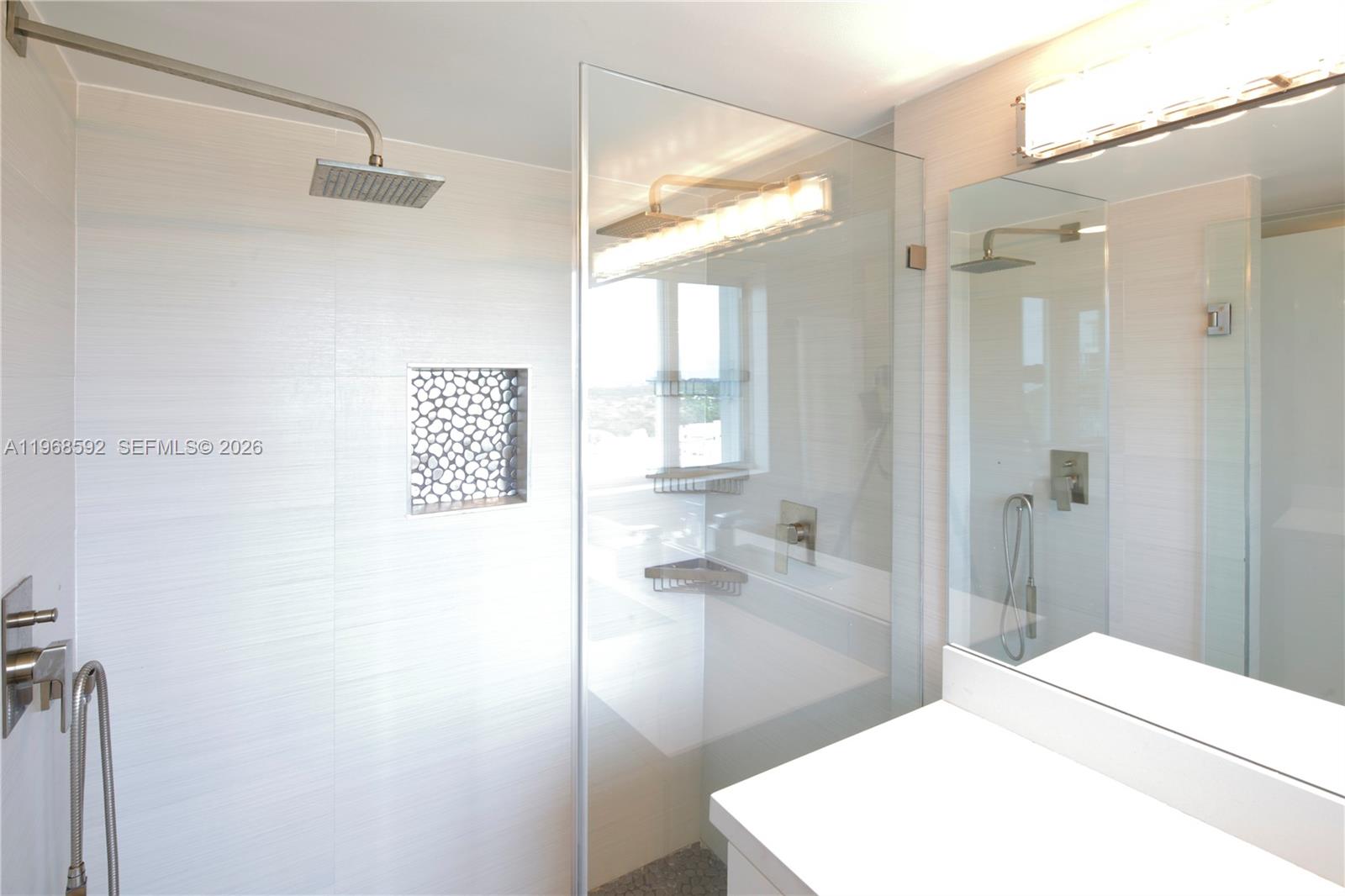 5900 Collins Avenue, Unit 1401 Miami Beach, FL 33140 - Photo 31 of 51 a bathroom with a sink a mirror and a shower