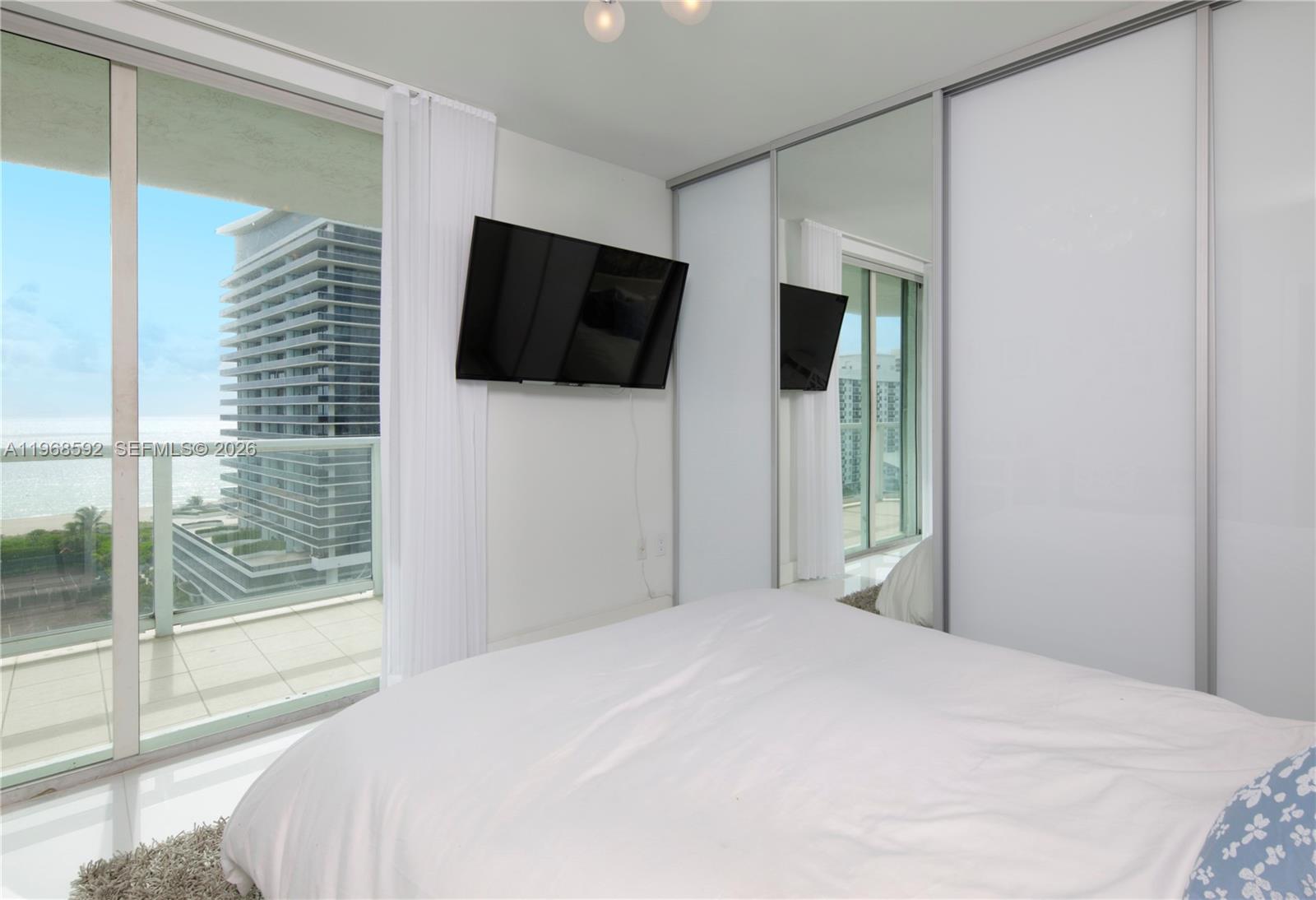5900 Collins Avenue, Unit 1401 Miami Beach, FL 33140 - Photo 33 of 51 a bedroom with a large bed and a flat tv screen