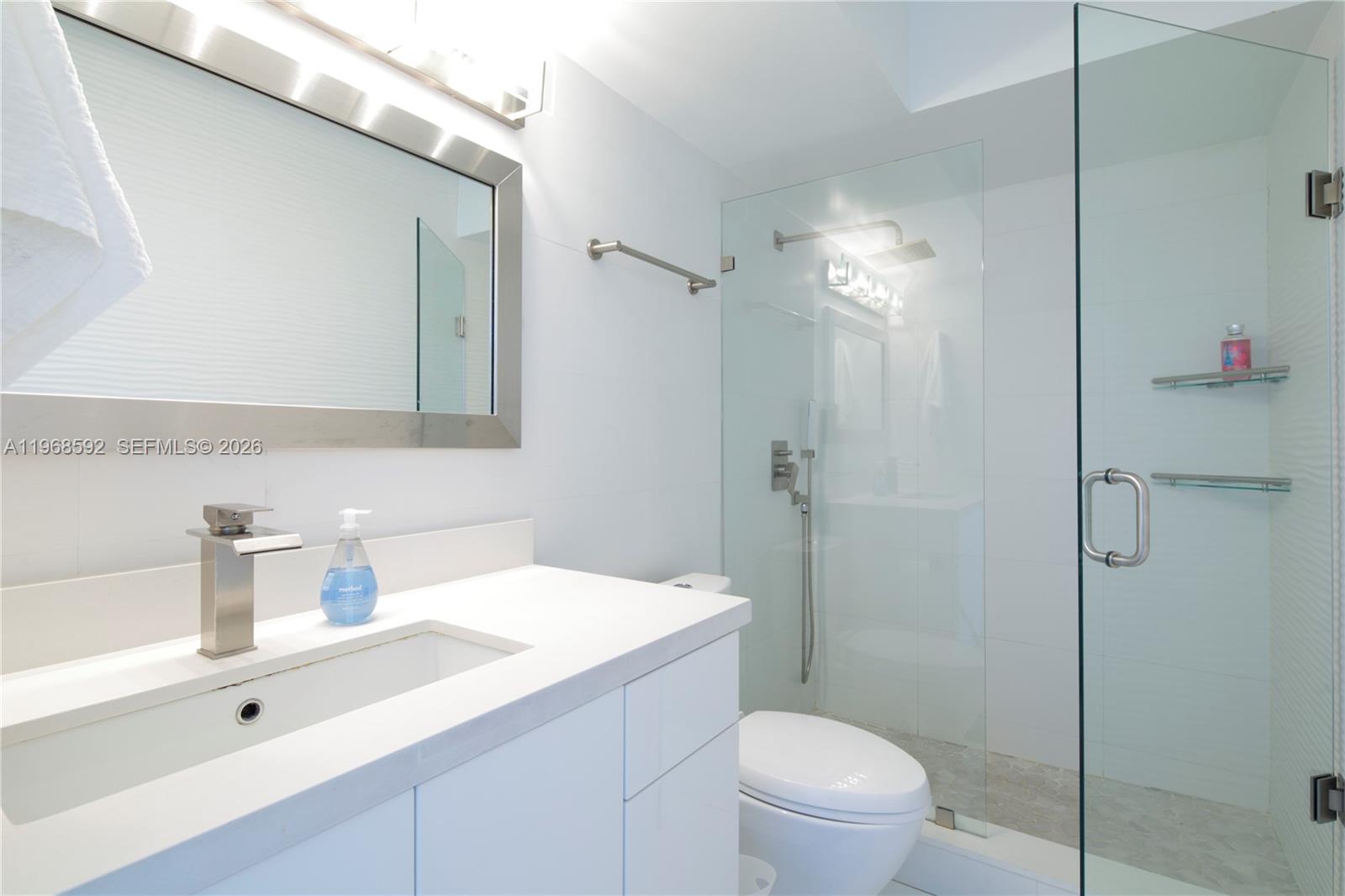 5900 Collins Avenue, Unit 1401 Miami Beach, FL 33140 - Photo 36 of 51 a bathroom with a sink a toilet a shower and a mirror