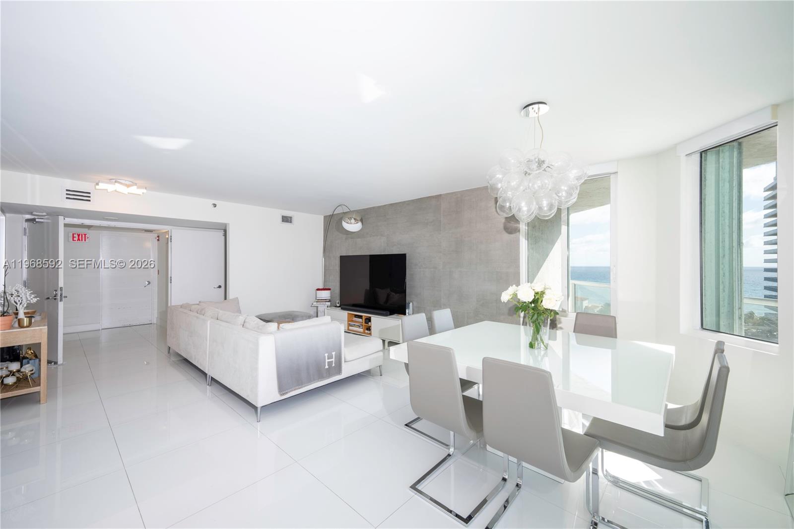 5900 Collins Avenue, Unit 1401 Miami Beach, FL 33140 - Photo 8 of 51 a living room with furniture a chandelier and a flat screen tv
