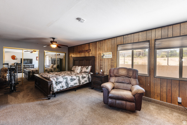 1470 Redwood Tree Street St. George, UT 84790 - Photo 14 of 53 Carpeted room featuring a ceiling fan with integrated lighting, wood panel accent wall, and two large windows with horizontal blinds
