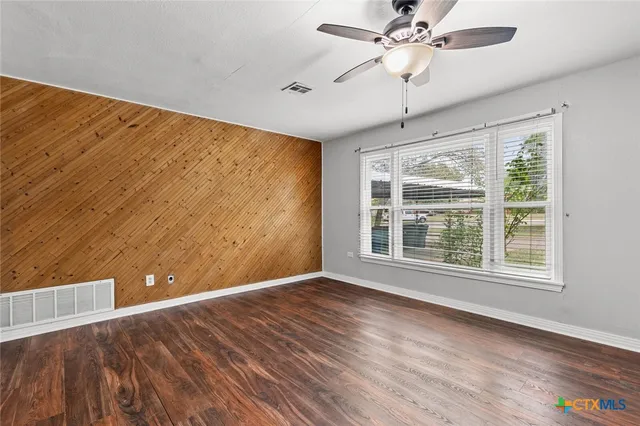 a view of an empty room with a window and wooden floor