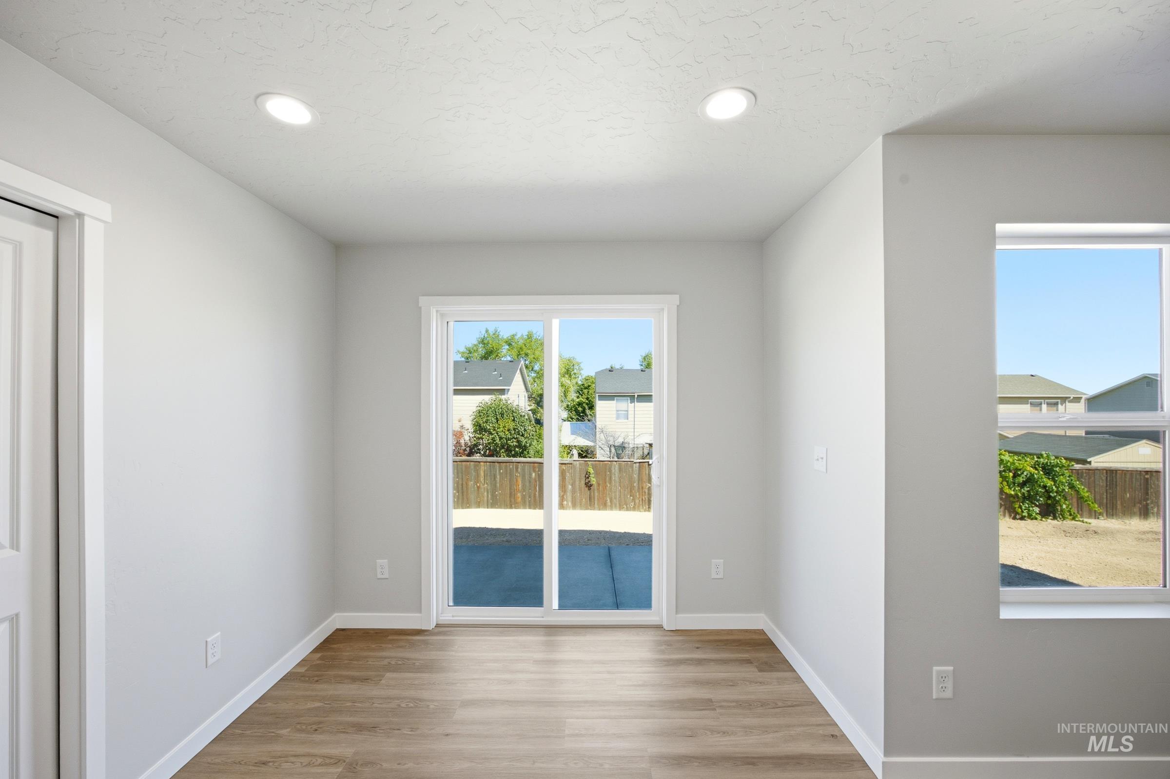 13333 Bank Street Caldwell, ID 83607 - Photo 11 of 29 Bright, open room with wood-finish flooring, recessed ceiling lighting, and dual glass doors with transom windows framing outdoor scenery