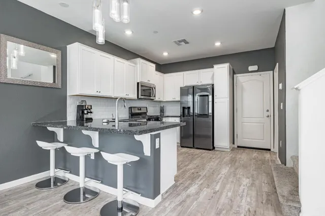 a kitchen with stainless steel appliances granite countertop a refrigerator a stove top oven a sink and dishwasher
