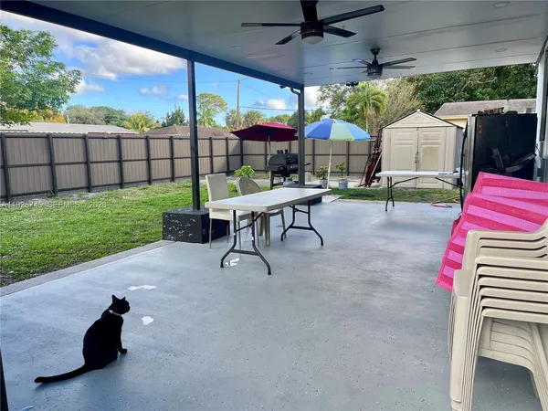 a view of a yard with a table and chairs under an umbrella