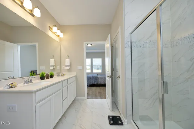 a large white bathroom with a double vanity sink a mirror and a shower