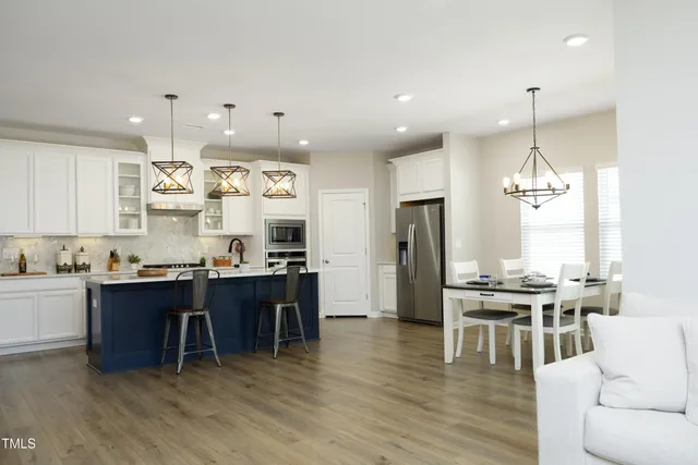 a kitchen with stainless steel appliances kitchen island granite countertop a table chairs sink and cabinets