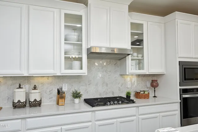 a kitchen with stainless steel appliances granite countertop white cabinets and a stove
