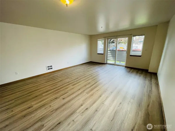 an empty room with wooden floor and windows