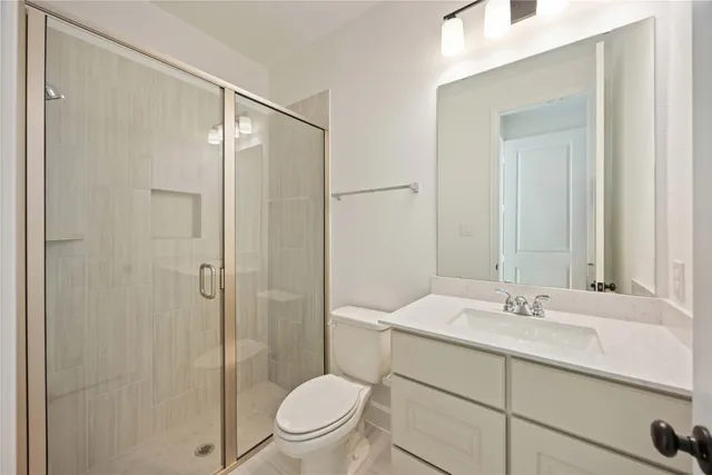 a bathroom with a shower sink vanity mirror and toilet