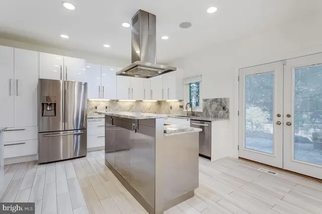 a kitchen with kitchen island a refrigerator a stove a oven and a sink with wooden floor