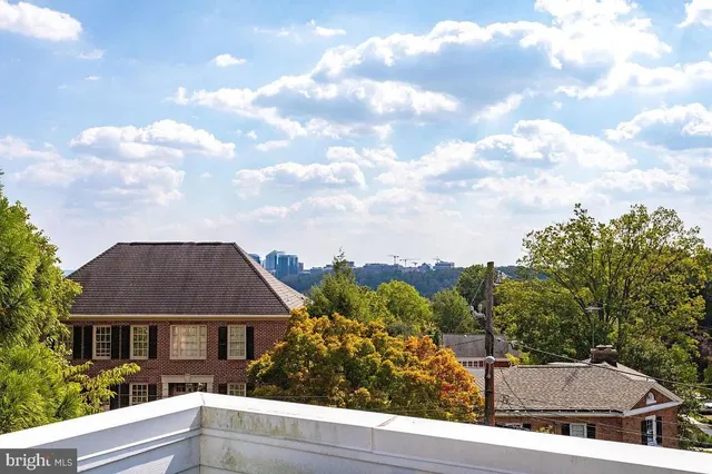 a view of a balcony with a couple of cars parked in front of house