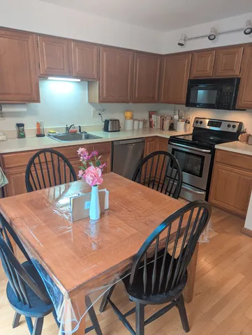 a kitchen with stainless steel appliances kitchen island granite countertop a dining table chairs and a refrigerator