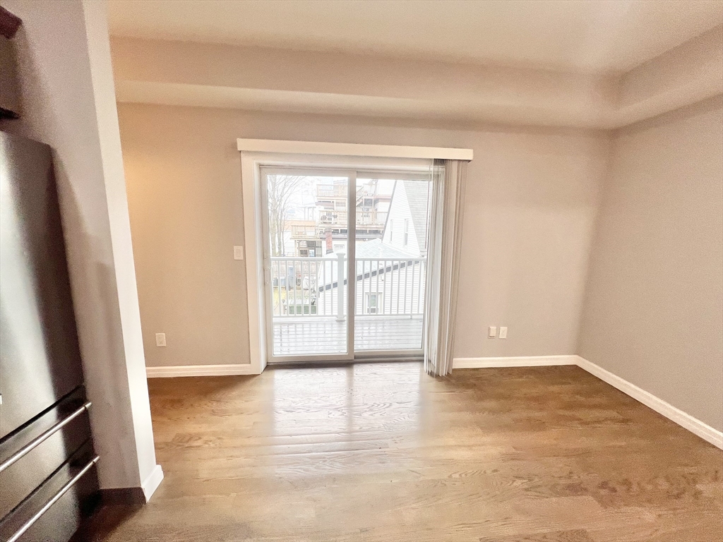 47-49 Walnut Street, Unit 2 Boston, MA 02122 - Photo 2 of 12 an empty room with wooden floor and windows