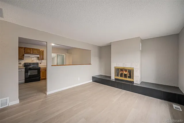 a view of a livingroom with wooden floor and a kitchen space