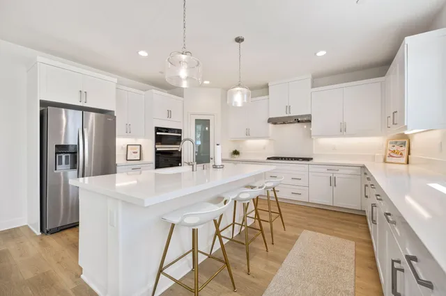 a kitchen with kitchen island a stove a table a sink refrigerator and cabinets