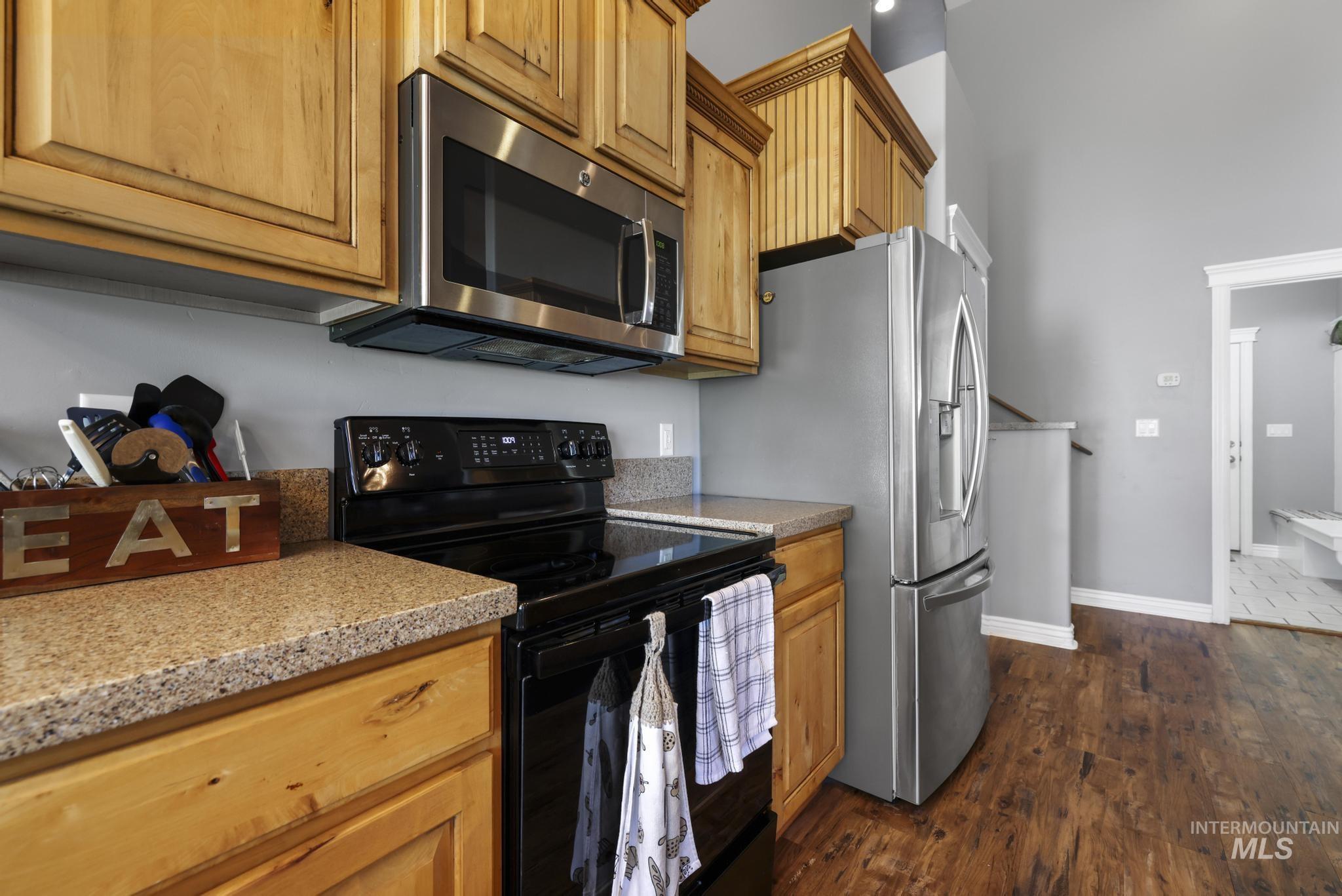 467 Wildrose Loop Twin Falls, ID 83301 - Photo 15 of 46 Kitchen featuring stainless steel appliances including a microwave and refrigerator, black electric range, wood cabinetry, and speckled countertops