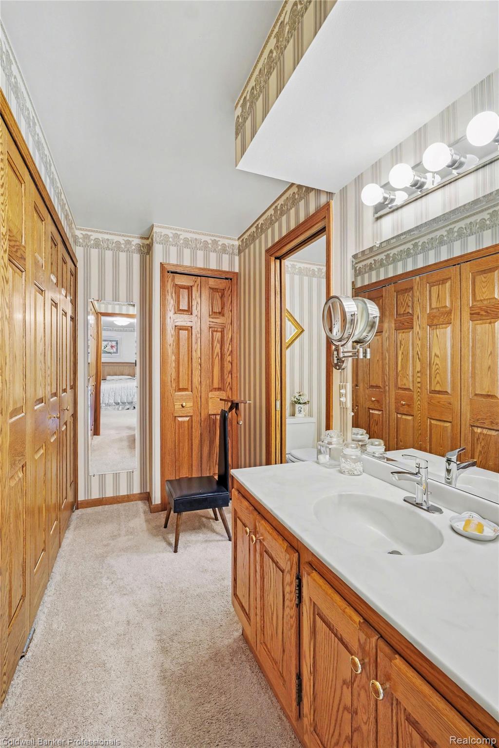 3583 Mitchell Road Metamora, MI 48455 - Photo 34 of 58 Bathroom vanity featuring a light-colored countertop with an integrated sink, polished chrome faucet, and wood-finish cabinetry