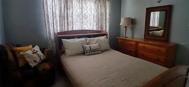 a bed sitting in a bedroom next to a window and dresser