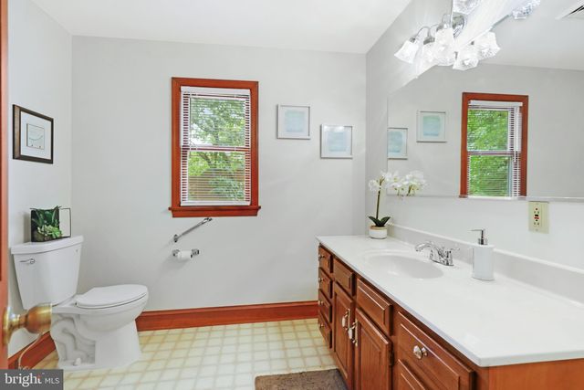 a bathroom with a sink a toilet a mirror and a window