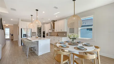a view of a dining room and livingroom with furniture wooden floor kitchen view