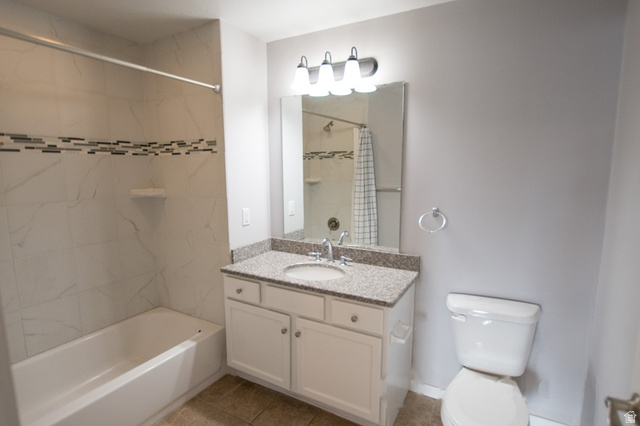 2150 South Main Street, Unit R405 Salt Lake City, UT 84115 - Photo 17 of 20 Bathroom featuring a tub/shower combination with tile surround and decorative accent band, a white vanity with a granite countertop and integrated sink, a wall-mounted mirror, and a modern light fixture