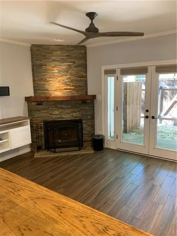 a view of an empty room with wooden floor fireplace and a window