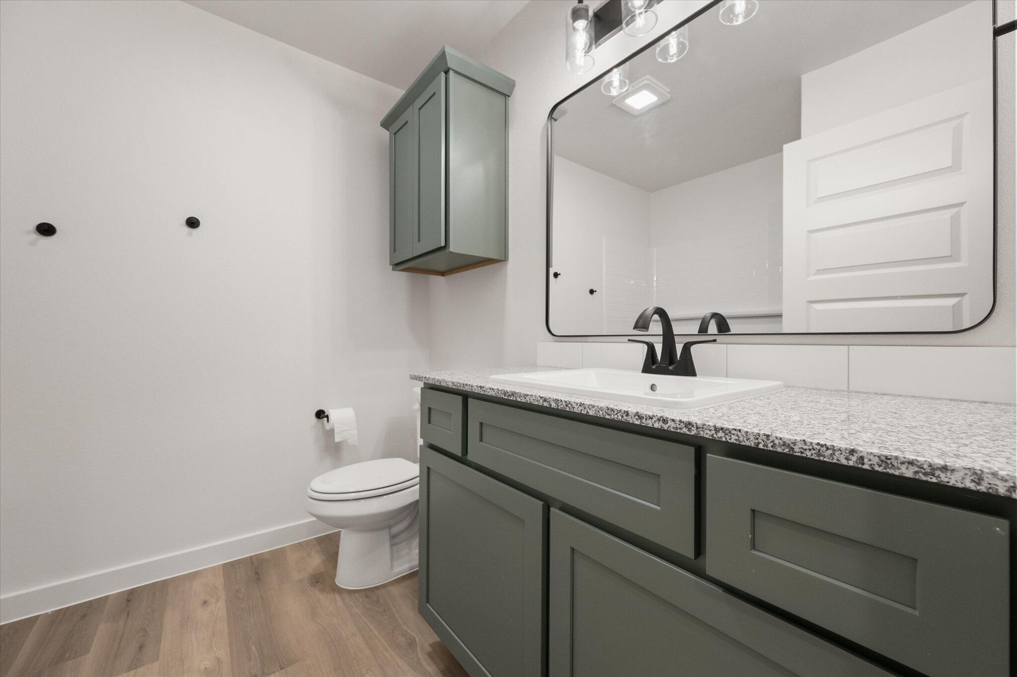 7003 53rd Street Lubbock, TX 79407 - Photo 23 of 25 a bathroom with a granite countertop sink a toilet and a mirror