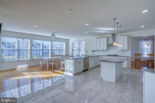 a kitchen with stainless steel appliances granite countertop a sink and dishwasher a stove top oven with white cabinets